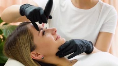 Eyebrow tattoo procedure with a permanent makeup machine.