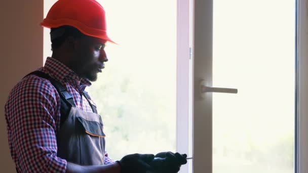 Afrykański Amerykański Robotnik Kombinezonach Instalujący Lub Regulujący Plastikowe Okna Salonie — Wideo stockowe