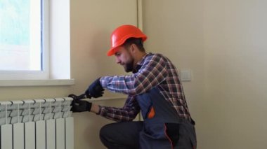 Tesisatçı yeni bir daireye radyatör kuruyor..