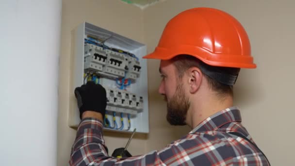戴着硬礼帽 穿着格子呢衬衫 在墙上安装电路板的专业工作者 — 图库视频影像
