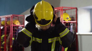 İtfaiyeci koruyucu üniformasını giyip itfaiyede beklerken harekete geçmeye hazırlanıyor.