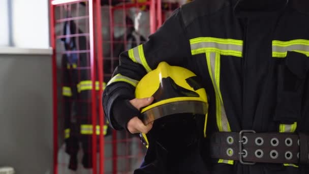 ステーションに立っている彼女の手のヘルメットと消防士 閉じる — ストック動画