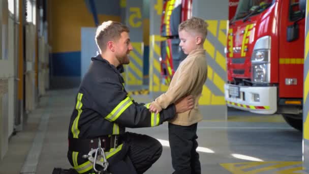 Πυροσβέστης Διδάσκει Ένα Μικρό Αγόρι Κανονισμούς Πυρασφάλειας — Αρχείο Βίντεο