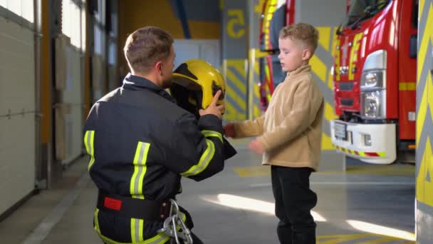 Firefighter Puts Protective Helmet Little Boy — Stock Video
