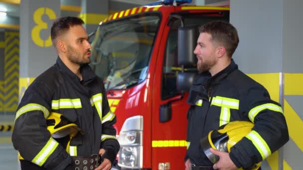 Två Brandmän Klädda Arbetskläder Med Hjälmar Brandstationen — Stockvideo