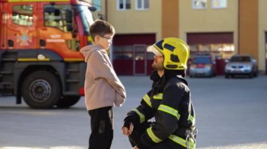 İtfaiyeci üniformalı küçük bir çocukla itfaiyede..