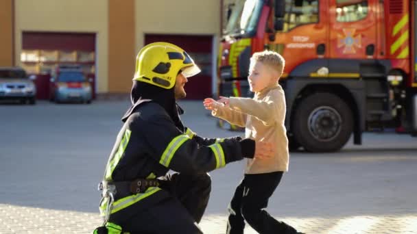 Vigile Del Fuoco Uniforme Abbraccia Bambino Vicino Pompiere Alla Stazione — Video Stock