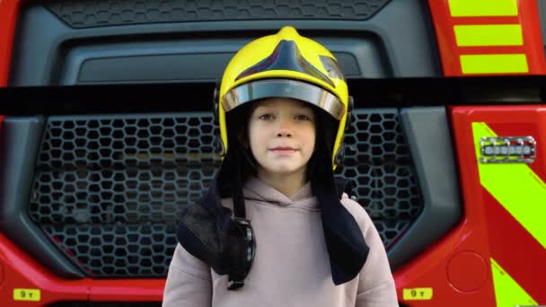 かわいい少年 消防士の服を着た子供は消防車で消防署にいる 子供たちの夢 — ストック動画