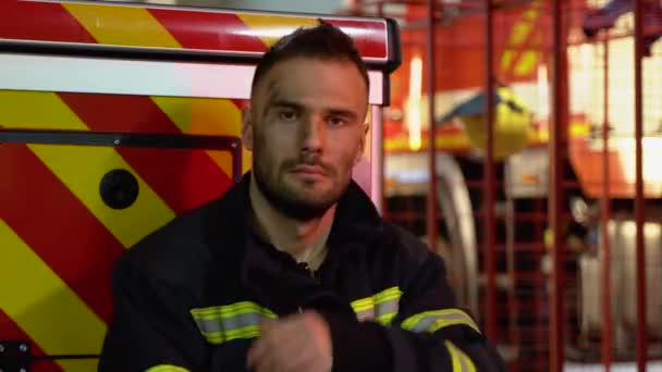 Уставший Пожарный Защитной Форме Смотрит Камеру Сидя Рядом Пожарной Машиной — стоковое видео