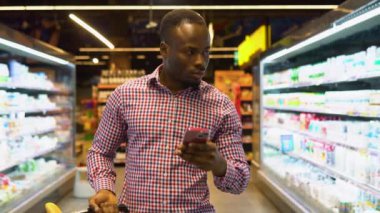 Akıllı telefonunda alışveriş sepeti okuma listesi olan Afrikalı Amerikalı bir adam..