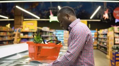 Siyah bir adam süpermarketten taze balık somonu alıyor.