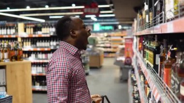 Süpermarketteki komik siyah adam şarap reyonundaki lüks alkolü seçiyor..