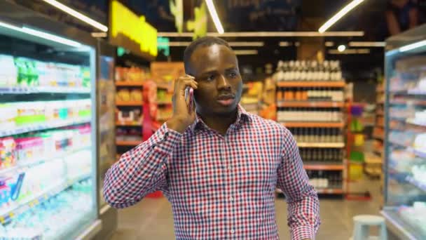 Красивий Чорний Чоловік Ходить Озирається Супермаркеті Розмовляє Телефону Своєю Дружиною — стокове відео