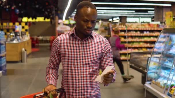 Потрясенный Черный Человек Смотрит Бумажный Чек Супермаркете После Покупок Роста — стоковое видео