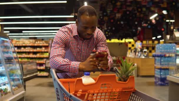 Siyah Adam Akıllı Telefonuyla Alışveriş Listesine Notlar Alır — Stok video