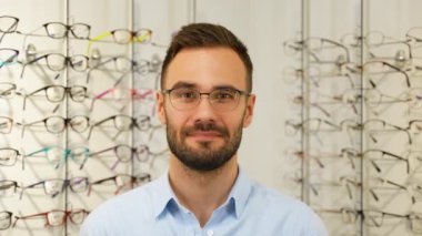 Optik dükkanında yeni özellikler seçen yakışıklı bir adamın portresi.