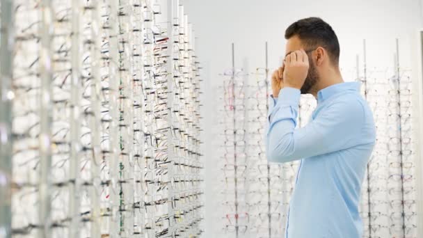 Vista Lateral Del Hombre Está Eligiendo Gafas Tienda Óptica — Vídeo de stock