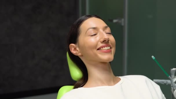 若い笑顔の女性が歯医者のオフィスで椅子に座っている 歯のケア 健康な歯 — ストック動画
