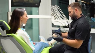 Diş hekimi ve hasta, arka planda tıbbi ekipmanlarla yapılan bir muayenede tedaviyi seçiyor.