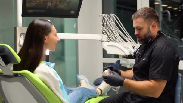 Дантист Показывает Пациентке Зубные Протезы Кронштейном Руках — стоковое видео