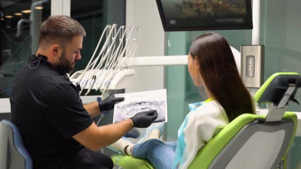 牙科医生解释在牙科诊所为病人提供的口腔护理服务 — 图库视频影像