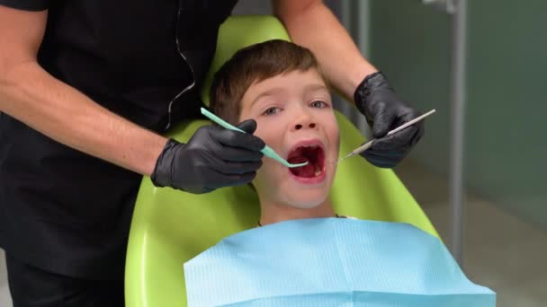 Симпатичный Мальчик Открытым Ртом Смотрит Сторону Пока Доктор Лечит Зубы — стоковое видео