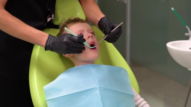 Smutny Chłopczyk Otwartymi Ustami Patrzy Bok Podczas Gdy Lekarz Leczy — Wideo stockowe