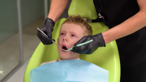 Smutny Chłopczyk Otwierający Szeroko Usta Podczas Leczenia Zębów Przez Dentystę — Wideo stockowe