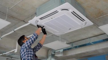 Asyalı işçi ofisindeki klimayı kontrol ediyor..