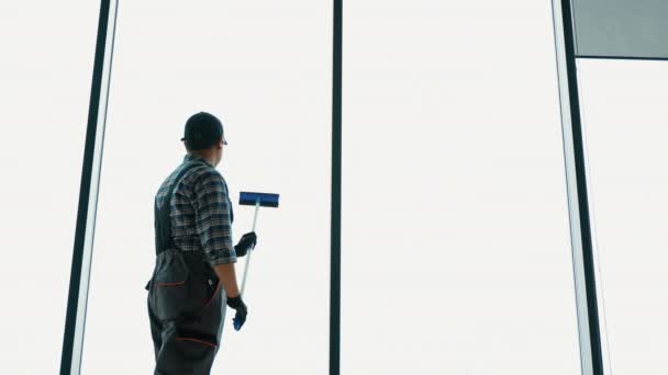 制服を着た男がスクレーパーで窓を洗っている 専門家の家かオフィスのクリーニング サービス — ストック動画