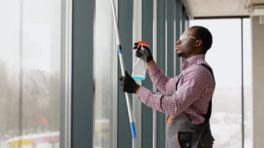 Afro-Amerikalı profesyonel temizlik işçisi pencereleri temizliyor..