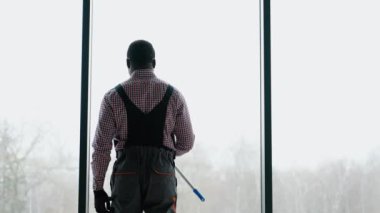 Afro-Amerikalı profesyonel temizlik işçisi pencereleri temizliyor..