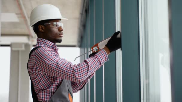 Black Worker Sealing Joints Office Window — Stock Video
