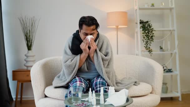 不健康な悲しいインドの若い男性は ナプキンでくしゃみ 平原の下で家でソファに座っています — ストック動画