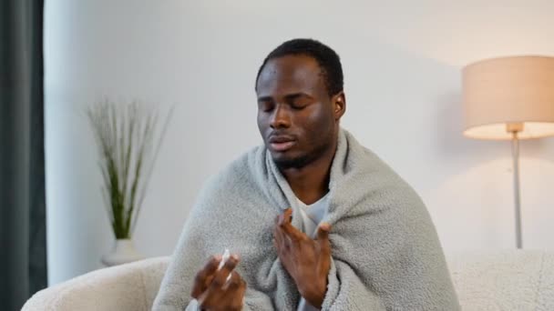 Μαύρος Άντρας Τυλιγμένος Κουβέρτα Ψεκάζει Ένα Ρινικό Σπρέι Ενώ Κάθεται — Αρχείο Βίντεο