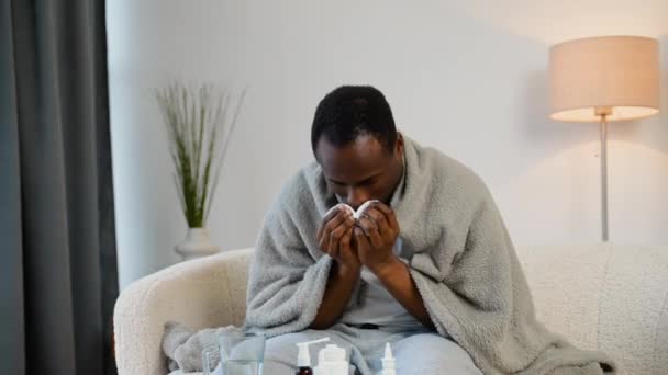 Hombre Negro Sienta Sofá Casa Bajo Una Manta Cuadros Estornudando — Vídeo de stock