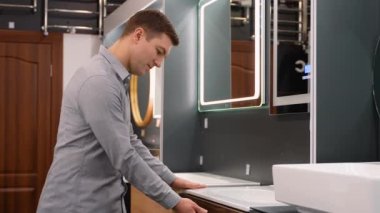 Hijyen dükkanında yeni banyo mobilyalarını seçen bir adam..