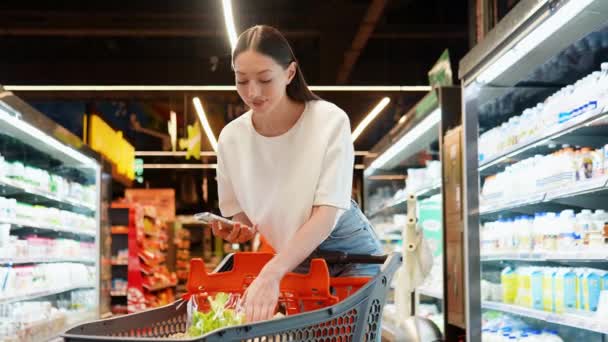 Mujer Bonita Supermercado Utiliza Teléfono Inteligente Comprador Compara Los Precios — Vídeos de Stock