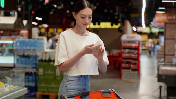 Vrouw Een Supermarkt Controleert Winkelbon — Stockvideo
