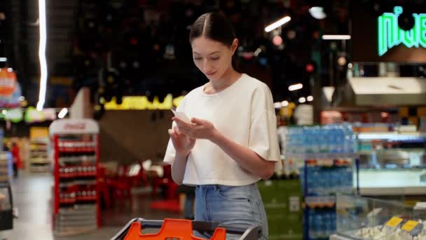 超市里的妇女检查购物收据和购物车 — 图库视频影像