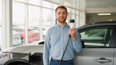 Şov salonunda şarj kablosu olan elektrikli arabanın mutlu sahibi..