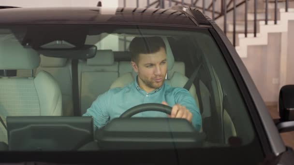 Een Vrolijke Man Imiteert Een Auto Rijdend Een Autodealer — Stockvideo