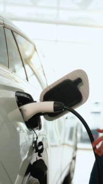 Adamın biri elektrik kablosunu galerideki elektrikli bir arabaya bağlıyor.
