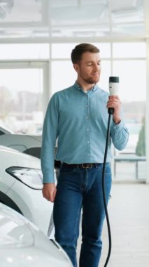 Şov salonunda şarj kablosu olan elektrikli arabanın mutlu sahibi.