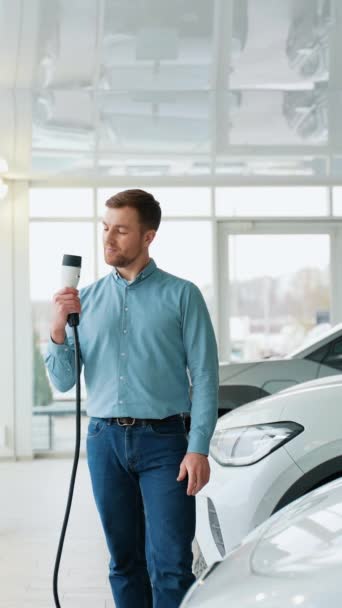 Bloger Samochodowy Lub Sprzedawca Demonstruje Kabel Ładowania Nowego Samochodu Elektrycznego — Wideo stockowe