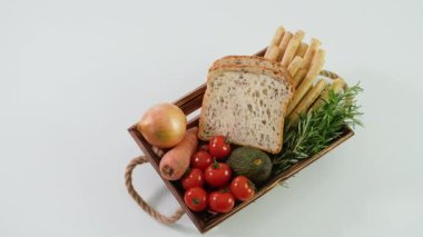 Taze sebzeli ahşap sepet, peynirli ekmek çubukları ve beyaz ekmek üzerine taze ekmek..