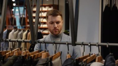 Moda mağazasında pantolon seçen şık bir adam..