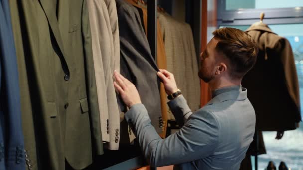 新しいジャケットを選ぶ若い男 — ストック動画