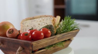 Taze sebzeli ahşap sepet, peynirli ekmek çubukları ve ekmek kızartma makinası mutfakta dönüyor..