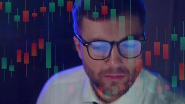 Kripto döviz borsası borsacısı gözlük takıyor bilgisayar ekranına bakıyor gözlüklere yansıyan ticaret grafikleri ile hisse senedi borsası finansal veri büyümesi kavramını izliyor.